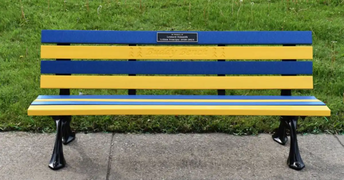 Blue and yellow buddy bench on a sidewalk